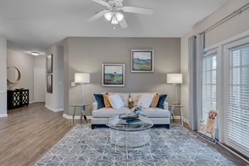 A living room with a white couch and a glass coffee table.